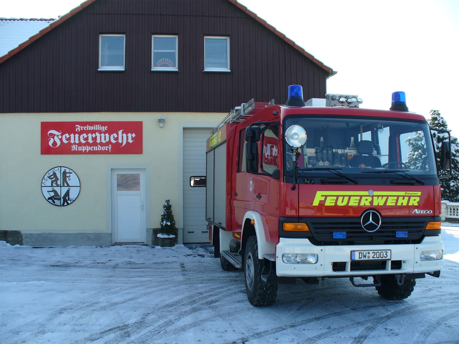 Feuerwehr Ruppendorf - Gerätehaus und Feuerwehrauto im Winter.