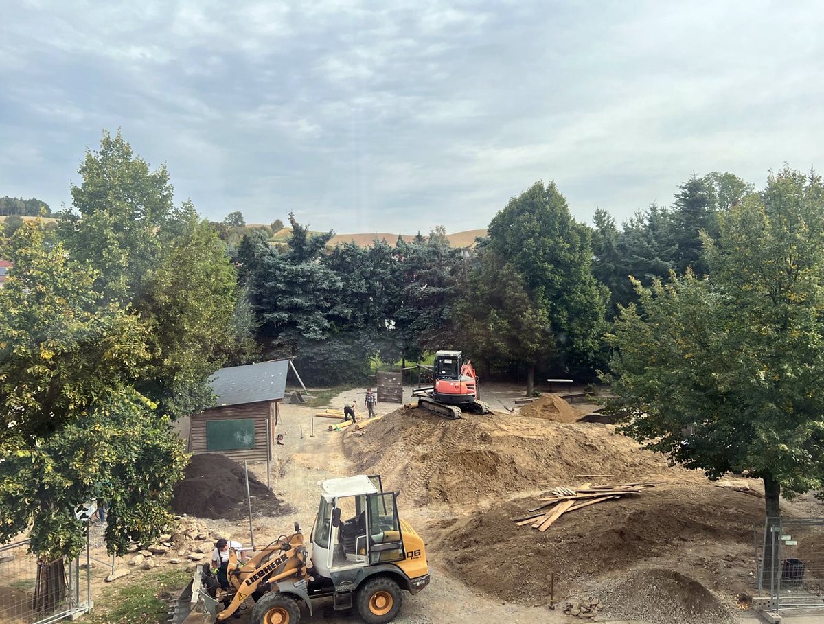 Überblick über die Schulhof-Baustelle mit Radlader und modellierten Hügeln
